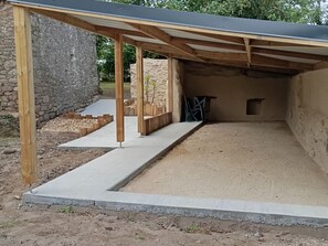 A covered outdoor area with a concrete floor, wooden posts, and a stone wall. - Cozy 6-Person Cottage in Chanverrie with Private Bathrooms, Kids' Play Area, and Terrace (Chanverrie)