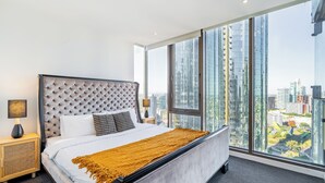 Une chambre d’hôtel moderne avec un grand lit, une vue sur la ville et une grande fenêtre.