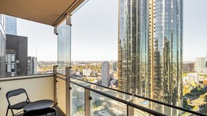 Un balcon offrant une vue sur le paysage urbain, avec de hauts immeubles et un ciel dégagé.