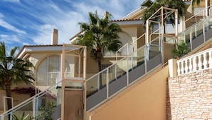 A multi-story building with a stone wall and a glass staircase.