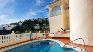 A swimming pool with a view of a hillside of white buildings under a clear sky.