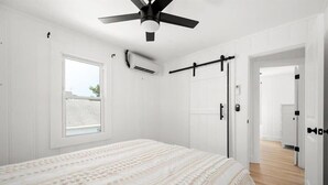 A bedroom with a bed, a ceiling fan, a window, and a door leading to another room. - Nicely Updated Two Bedroom Midtown Oceanside Condo (Ocean City)