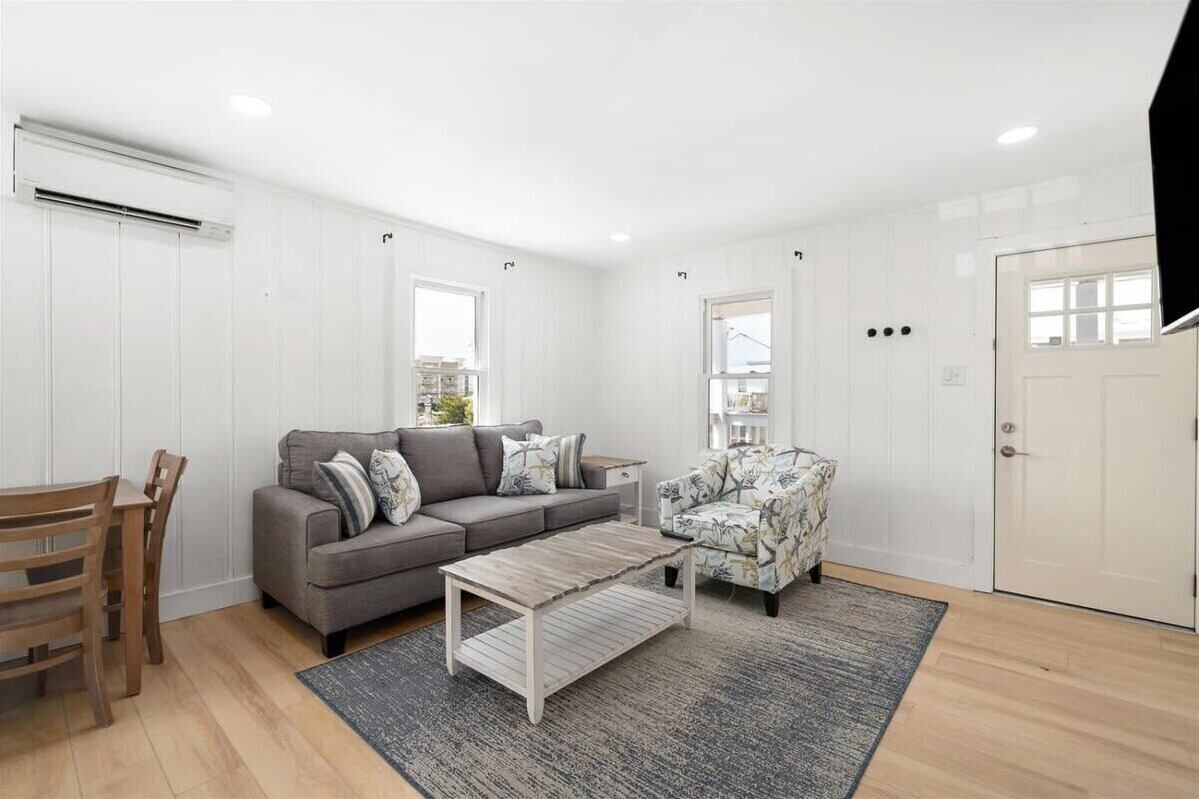 A modern living room with a grey sofa, floral armchair, and a wooden coffee table.