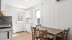 A modern kitchen with white cabinetry, a wooden dining table, and chairs. - Nicely Updated Two Bedroom Midtown Oceanside Condo (Ocean City)