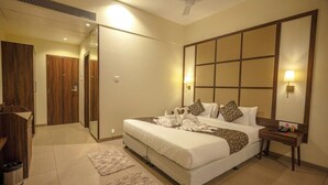 Una habitación de hotel con una cama grande, una mesita de noche, un espejo y un ventilador de techo.