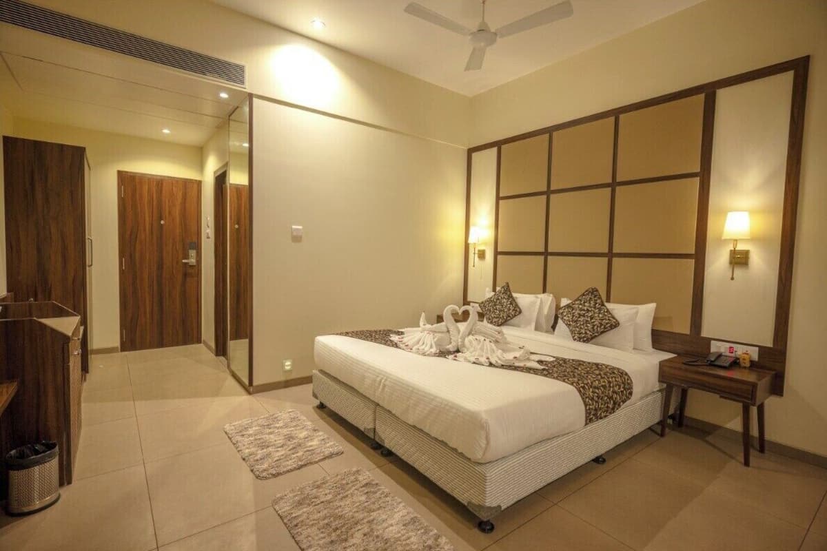 A hotel room with a large bed, a bedside table, a mirror, and a ceiling fan.