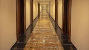 Un largo y estrecho pasillo con puertas de madera a ambos lados y un suelo de mármol pulido.