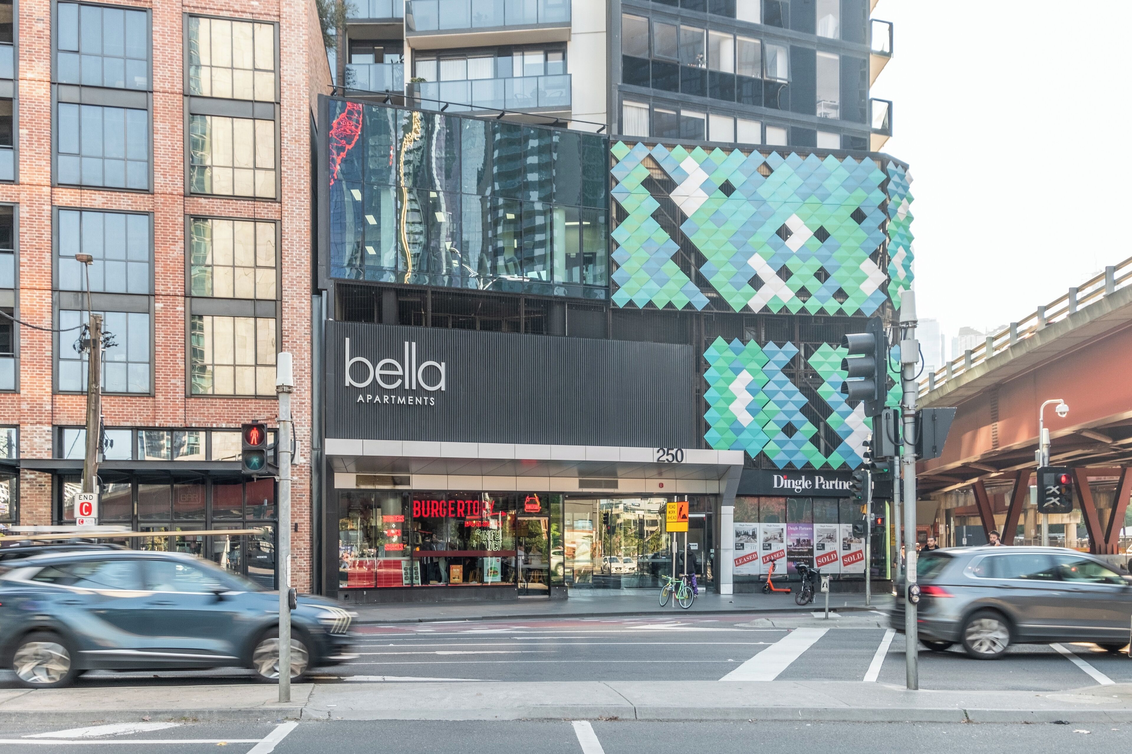 Een modern gebouw met een glazen gevel, een 'bella' bord en een 'Burger King' aan de overkant van de straat.