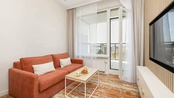 Ein modernes Wohnzimmer mit einer Couch, einem Couchtisch und einem großen Fenster mit Vorhängen.