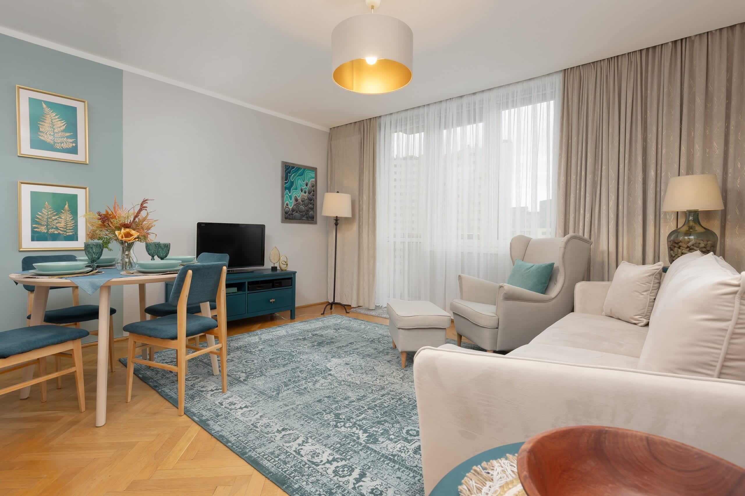 A modern living room with a sofa, chairs, a TV, and a dining area with a table and chairs.