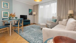 Una sala moderna con sofá, sillas, televisor y comedor con mesa y sillas.
