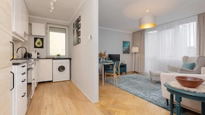 Un apartamento moderno con cocina, comedor y sala de estar. Incluye lavadora, mesa de comedor y sofá.