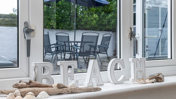 A window sill with the word "BEACH" spelled out in letters, surrounded by seashells and driftwood. - Tan Y Wylan -  a bungalow that sleeps 6 guests  in 3 bedrooms (Rhosneigr)