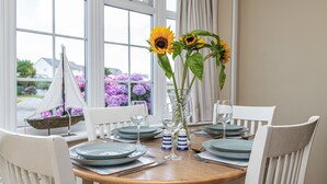 A dining table set with plates, glasses, and a vase with sunflowers. - Tan Y Wylan -  a bungalow that sleeps 6 guests  in 3 bedrooms (Rhosneigr)