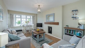 A living room with a sofa, a coffee table, a TV, a fireplace, and a bookshelf. - Tan Y Wylan -  a bungalow that sleeps 6 guests  in 3 bedrooms (Rhosneigr)