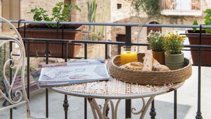Ein Balkon mit Tisch, Stühlen und einem Korb mit Brot und Getränken.
