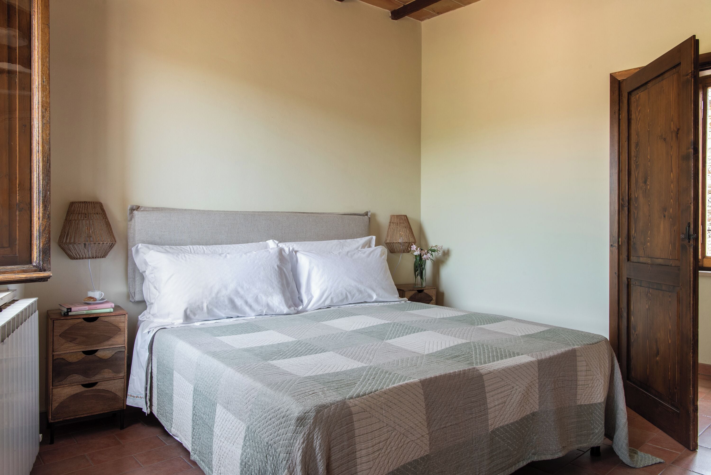 Un dormitorio con cama, mesitas de noche, una puerta de madera y un radiador.