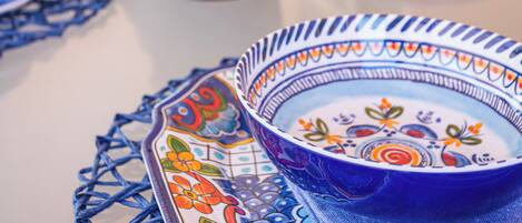 A table set with blue and white patterned tableware, a potted plant, and a blue chair.