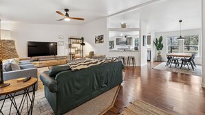 Ein modernes Wohnzimmer mit Sofa, Fernseher und Essbereich.
