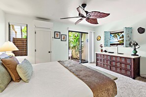 A bedroom with a bed, a ceiling fan, a dresser, a TV, and a view of the outdoors. - Spacious 1bd, ground floor, lanai, walk to beach (Kihei)