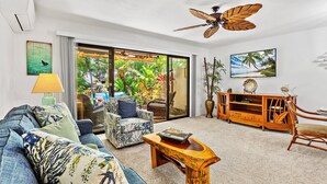 A living room with a sofa, armchair, wooden coffee table, and a ceiling fan.