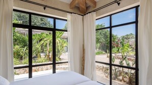 A room with a large bed, two windows with white curtains, and a view of tropical plants and trees. - Villa in Alguazas with 7 bedrooms sleeps 14 (Alguazas)