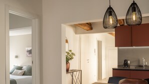 A modern kitchen with a built-in oven, a dining table with a brown bowl, and a small side table with a plant. - Sant'Aponal Cozy Apartment with Terrace R&R (Venecia)