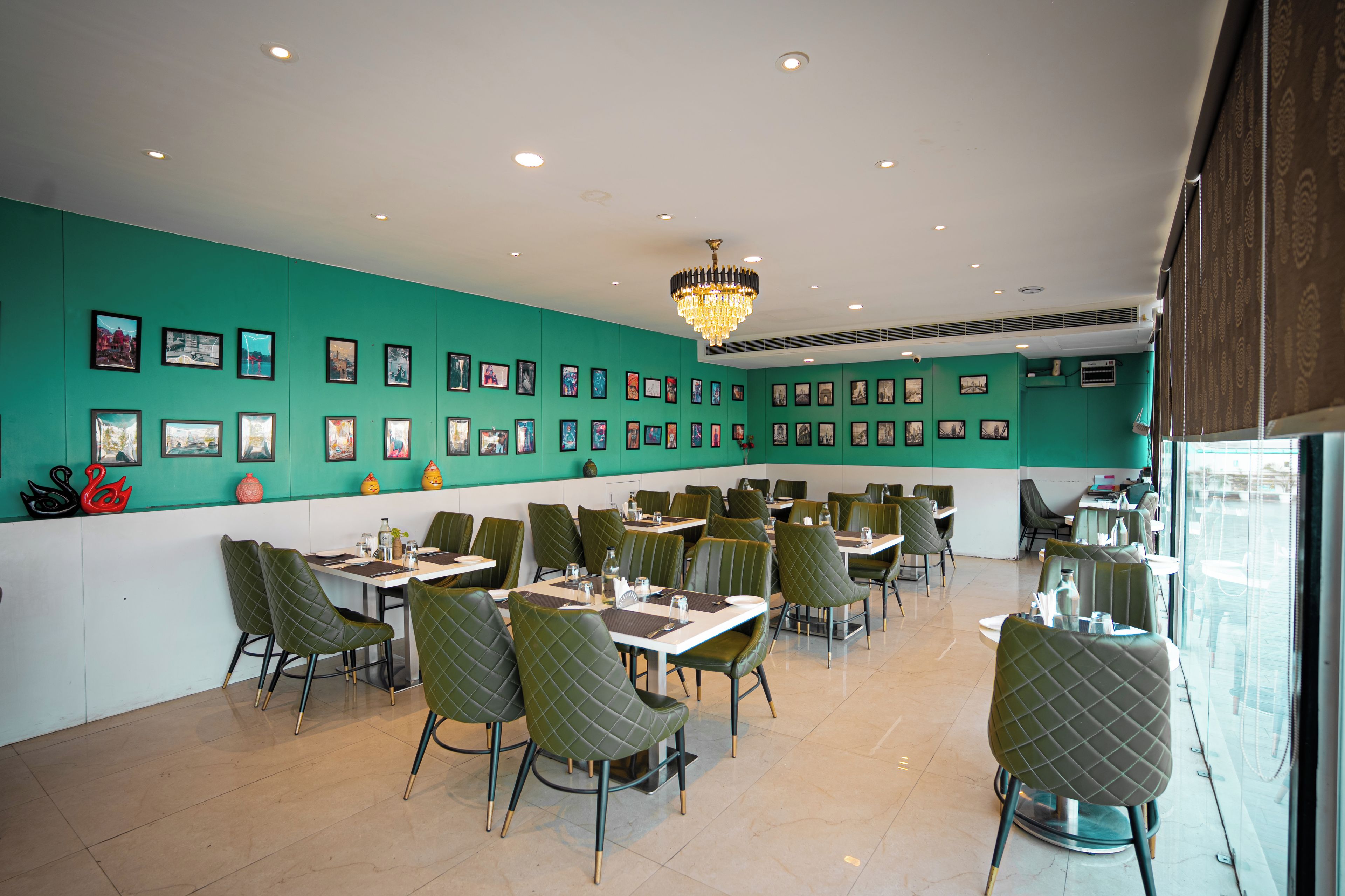 A restaurant with teal walls, multiple dining tables, and chairs.