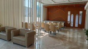Un hall espacioso con zona de estar, mostrador de recepción y una moderna pared de madera con listones verticales.