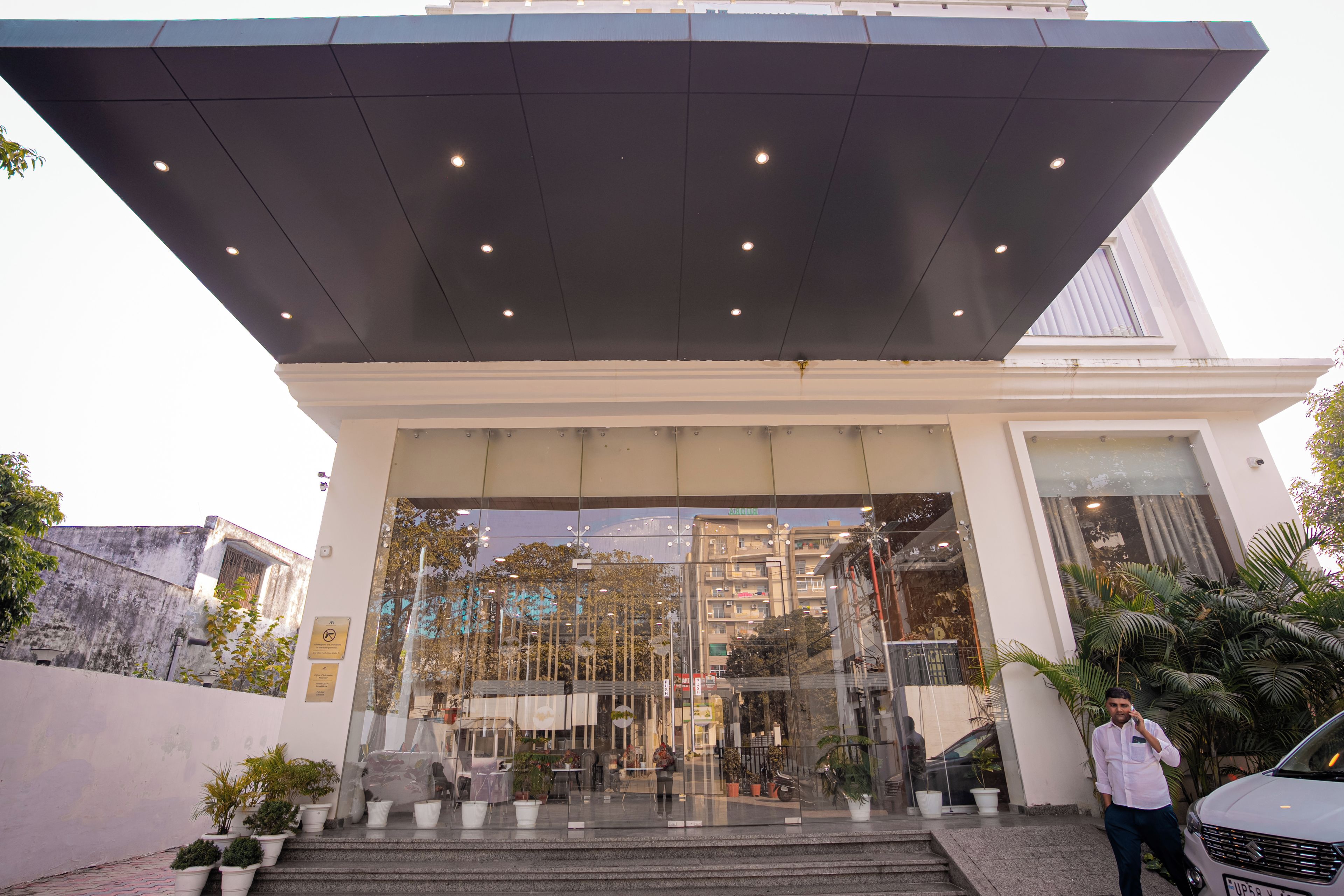 A hotel entrance with a glass facade, steps leading up to the entrance, and a covered area above.