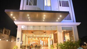 Un hotel moderno con fachada de vidrio, una zona de recepción y un balcón visible.