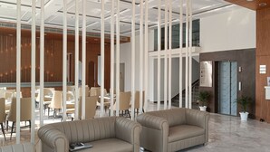 Un moderno vestíbulo de hotel con mostrador de recepción, zona de estar y una escalera.