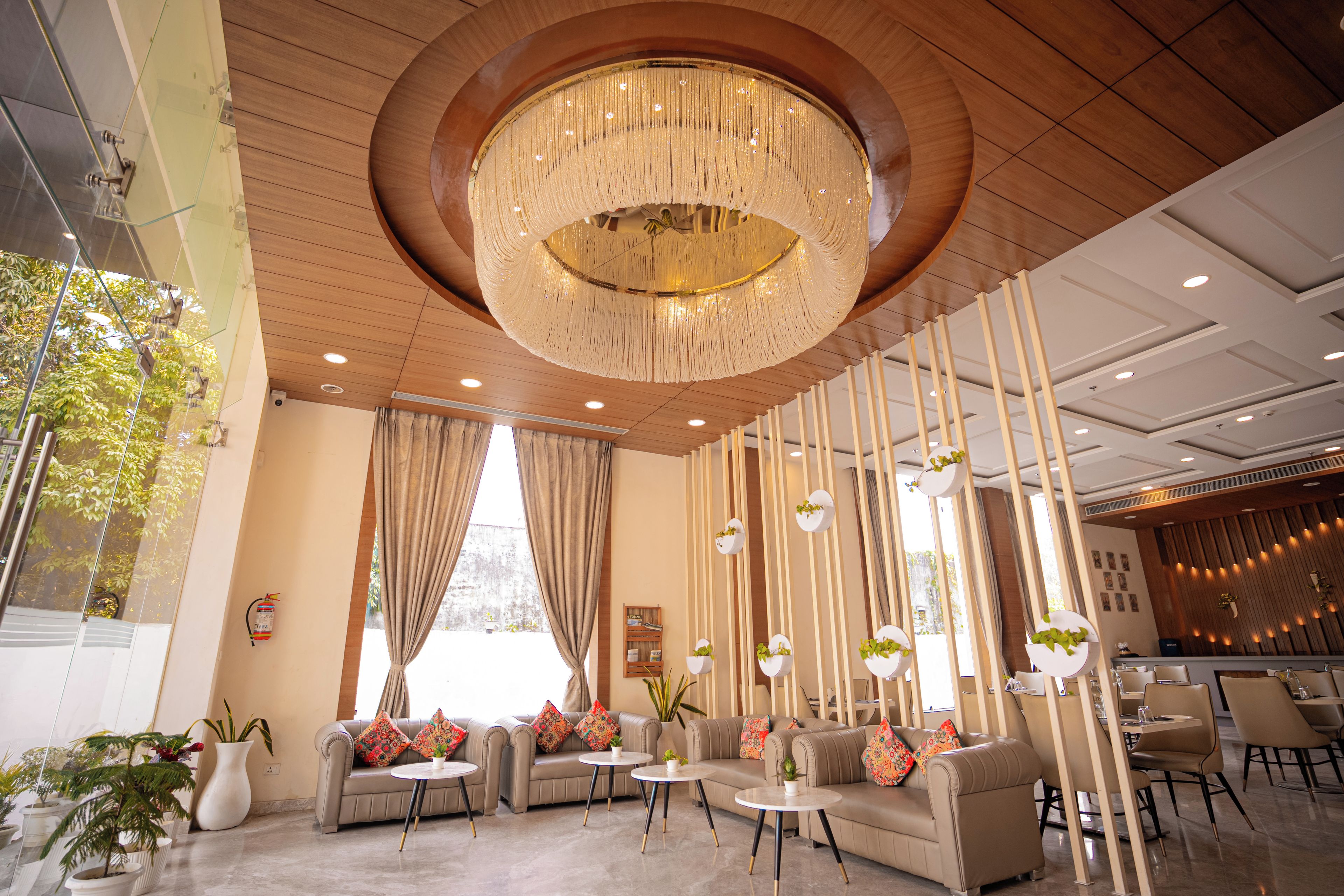A modern interior with a central chandelier, sofas, tables, and vertical light fixtures.