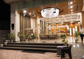 A modern lobby with a seating area, a staircase, and a reception desk.