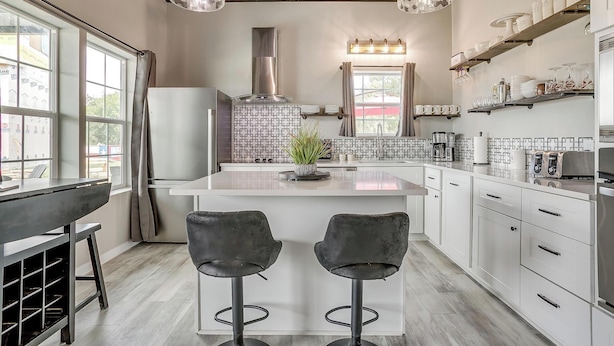 A modern kitchen with a central island, bar stools, a built-in stove, and pendant lighting.