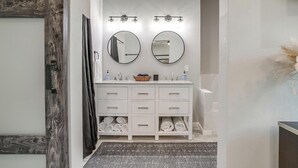 A bathroom with a white vanity, two mirrors, a towel rack, and a shower curtain.