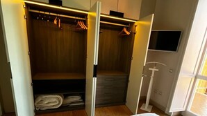 A bedroom with a bed, a wardrobe with hanging space, and a TV mounted on the wall.