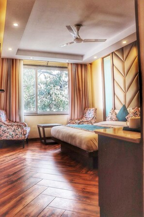 A modern bedroom with a bed, a chair, a table, and a ceiling fan. - The Kenilworth Mussoorie by Stotrak (Dehradun)