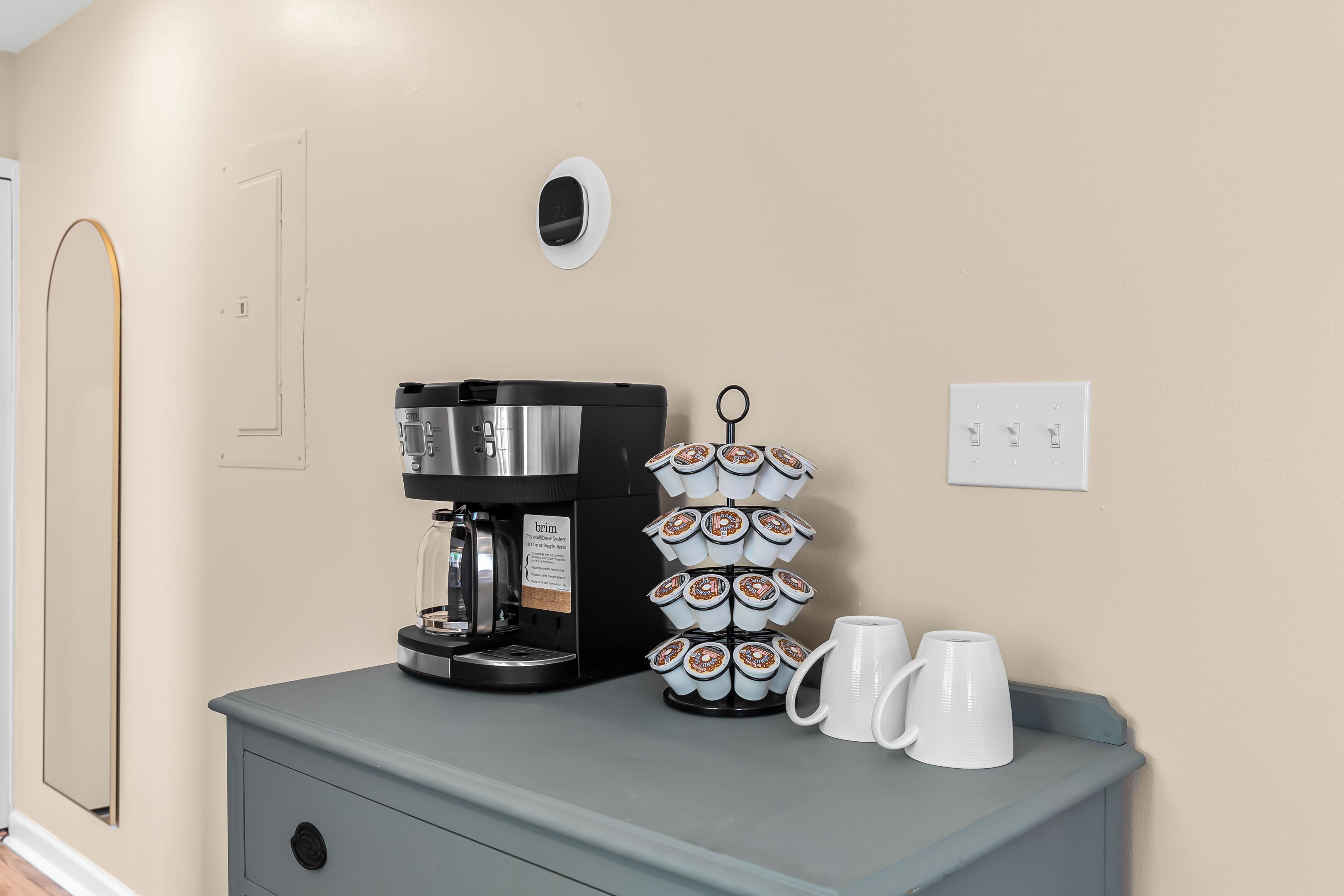 A kitchenette with a coffee maker, a mug rack, and two mugs on a counter.