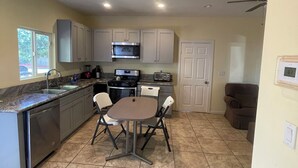 A modern kitchen with a central island, white cabinets, and a dining area with four chairs. - Guest house at a private resort in Good Hope Area (Perris)