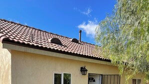 A single-story house with a tiled roof, a bench, a trash bin, and a small garden area. - Guest house at a private resort in Good Hope Area (Perris)