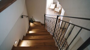 A wooden staircase with a metal railing leading to a room with a tiled floor. - Casa Marinari (Scalea)