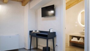 A modern bathroom with a large mirror, a sink, and a toilet. There is a small table with a kettle and cups. - Casa Marinari (Scalea)