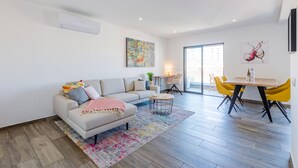 Un salon moderne avec un canapé, une table basse et un coin repas avec des chaises jaunes.