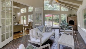 A spacious room with a high ceiling, large windows, a fireplace, and a seating area with a sofa and chairs. - 12 Haul Away - 5 Bedroom - Private Pool, Lagoon View Short Walk to the Beach (Hilton Head)