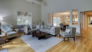 A spacious living room with a large sectional sofa, a coffee table, and a dining area with chairs. - 12 Haul Away - 5 Bedroom - Private Pool, Lagoon View Short Walk to the Beach (Hilton Head)