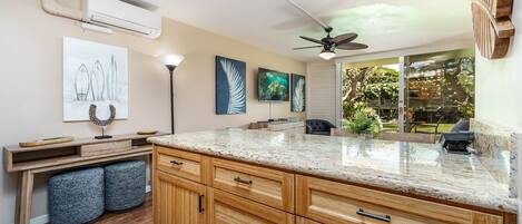 A kitchen with wooden cabinets, a granite countertop, and artwork on the walls.