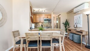 Una cocina moderna con armarios de madera, microondas integrado y comedor con mesa y sillas de madera.
