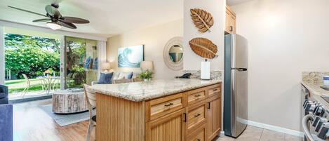 A modern kitchen with wooden cabinets, a granite countertop, and a stainless steel refrigerator.