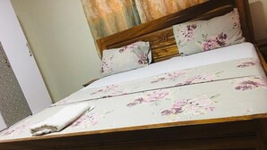 Una cama con ropa de cama floral y un cabecero de madera.